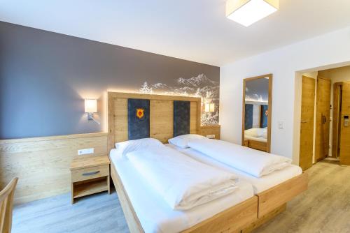 a bedroom with a large bed with white sheets at Hotel & Gasthof Taferne in Schladming