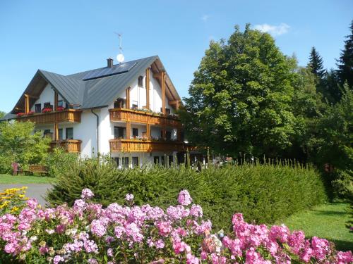 una casa con balcone e fiori di fronte di Hotel Bergblick a Warmensteinach