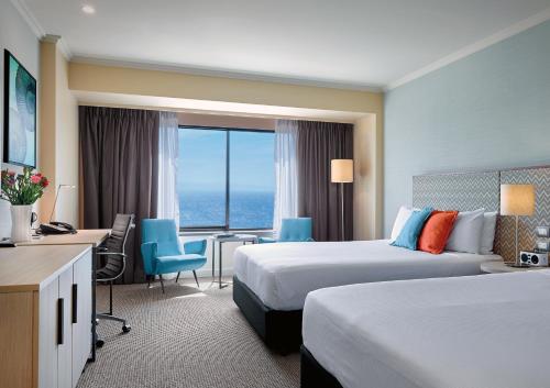 ein Hotelzimmer mit 2 Betten und einem Schreibtisch in der Unterkunft Stamford Grand Adelaide in Adelaide