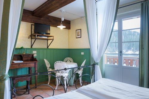 a bedroom with a bed and a desk and a window at Quinz - Locanda Al Lago in Misurina