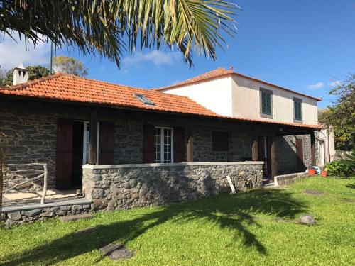 une maison en pierre avec un toit rouge dans l'établissement Casa dos Reis, à Calheta