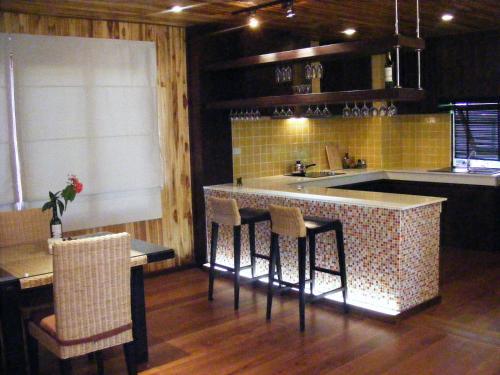 a kitchen with a bar with chairs and a sink at Baan Nana Villa in Mae Nam