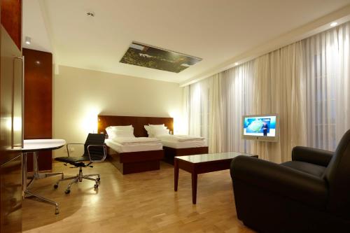 a hotel room with a bed and a couch and a tv at Grand Hotel Mussmann in Hannover