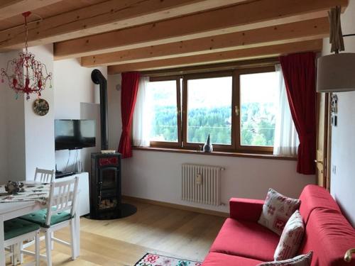 sala de estar con sofá rojo y mesa en Casa Romeo, en San Vito di Cadore