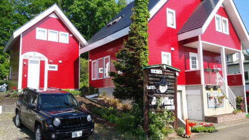 una jeep nera parcheggiata di fronte a una casa rossa di Cottage Morino Nakamatachi a Furano