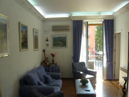 - un salon avec un canapé bleu et une chaise dans l'établissement Hostal Triana, à Madrid