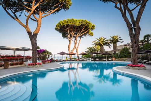 uma piscina com árvores ao fundo em Cala del Porto Punta Ala em Punta Ala