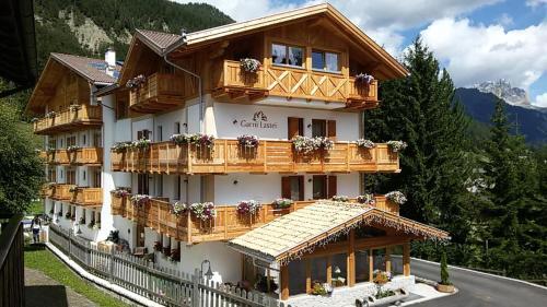 een groot gebouw met houten balkons op een berg bij Hotel Garni Lastei in Pozza di Fassa