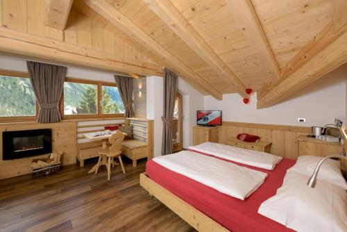 een slaapkamer met een groot bed en een bureau bij Hotel Garni Lastei in Pozza di Fassa