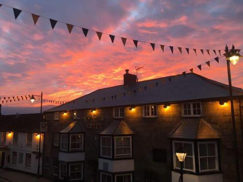 um edifício com uma série de bandeiras em frente a um pôr-do-sol em Tyacks Hotel em Camborne