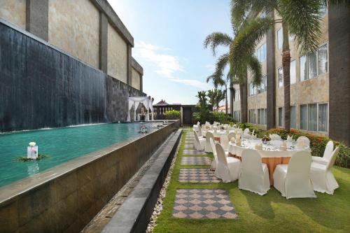 un restaurant avec des tables et des chaises à côté d'une piscine dans l'établissement Aston Denpasar Hotel & Convention, à Denpasar