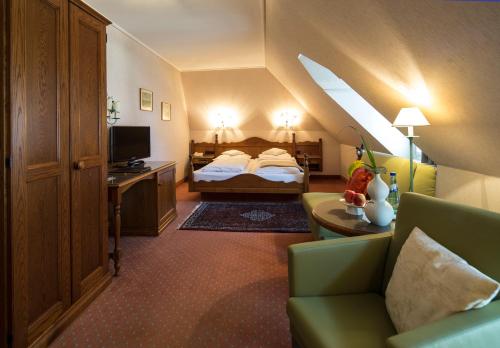 una camera d'albergo con letto, divano e TV di Hotel und Weinhaus Zum Krug a Eltville