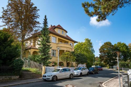 une maison jaune avec des voitures garées devant elle dans l'établissement Pension Villa Gisela, à Weimar