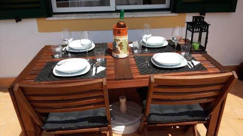 una mesa de madera con platos y vasos. en Villa Figueira, en Portimão