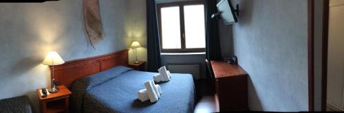 Kleines Zimmer mit einem blauen Bett und einem Fenster in der Unterkunft Hotel Clari in Claviere