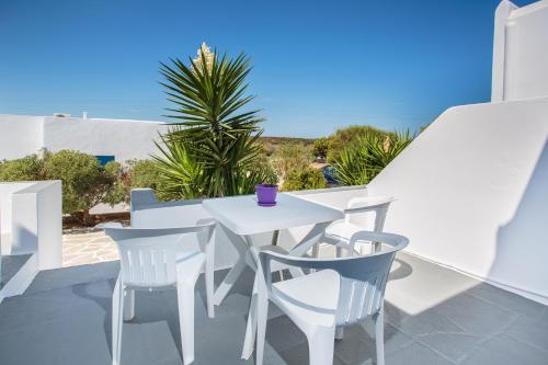 - une table et des chaises blanches sur un balcon donnant sur l'océan dans l'établissement Fragos Apartments, à Santa Maria