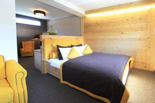 a bedroom with a large bed and a yellow chair at Hotel Sommerhof in Gosau