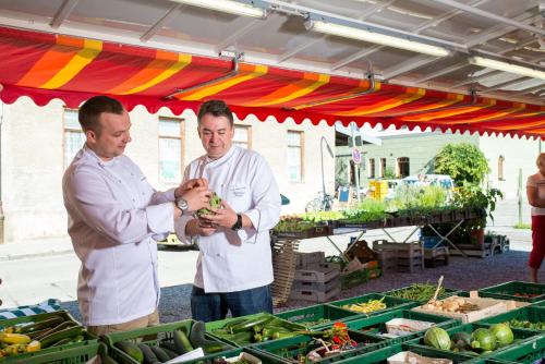 Zwei Männer stehen unter einem Zelt mit Produkten. in der Unterkunft Hotel Johannisbad in Bad Aibling