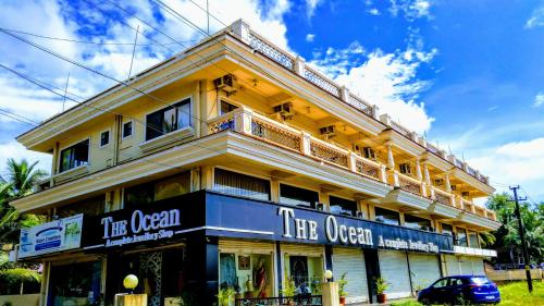 a large yellow building with a sign for the opera at Ocean Crest Hotel in Colva