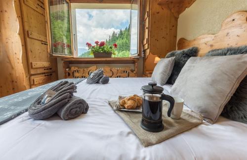 een bed met een koffiepot en een bord eten erop bij Chalet Bluebell in Les Gets