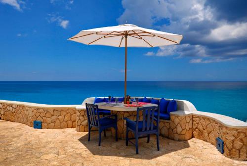 - une table et des chaises sous un parasol sur la plage dans l'établissement The Caves, à Negril