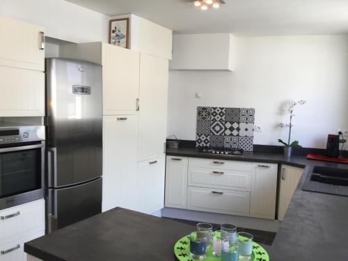 a kitchen with white cabinets and a stainless steel refrigerator at chambre d'hôte-abc in Reims