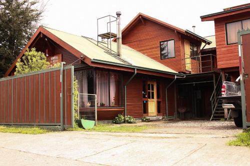 een houten huis met een hek ervoor bij Hostal el Nogal Pucón in Pucón