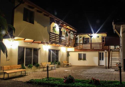 a building with two benches and a balcony at night at Pensiunea Mariana in Ocna Şugatag