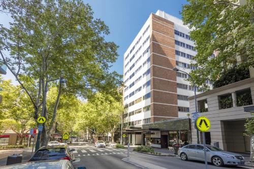 une rue avec des voitures garées devant un grand bâtiment dans l'établissement Macleay Hotel, à Sydney