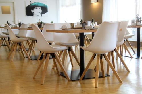 une salle à manger avec une table et des chaises blanches dans l'établissement Schlossberghotel Greiz, à Greiz