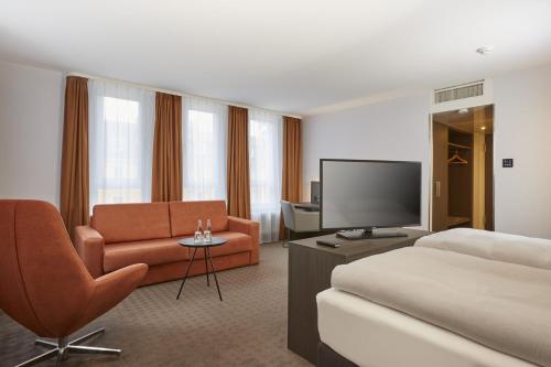 una camera d'albergo con letto e TV di H4 Hotel Residenzschloss Bayreuth a Bayreuth