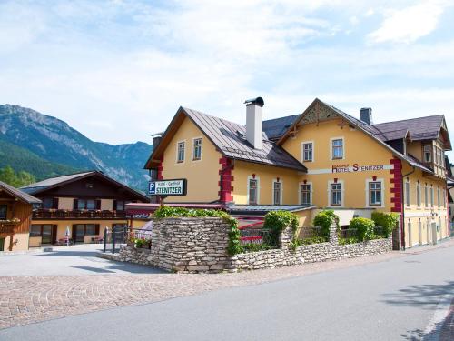 duży żółty budynek po stronie ulicy w obiekcie Hotel Gasthof Stenitzer w mieście Haus im Ennstal