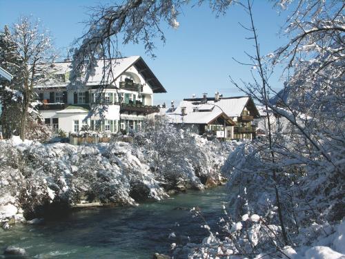 uma casa numa colina coberta de neve ao lado de um rio em Hotel Aschenbrenner em Garmisch-Partenkirchen