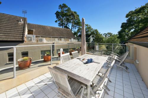 a deck with a wooden table and chairs on a balcony at Tranquil Little Cove Unit, Pool Escape in Noosa Heads