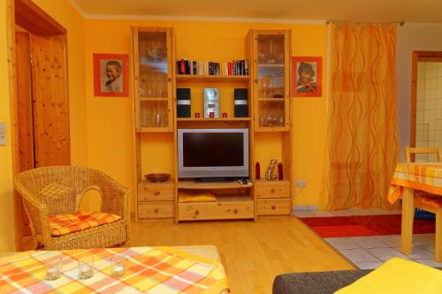 a living room with a television on a wooden entertainment center at Ferienwohnung Kaufmann in Baiersbronn