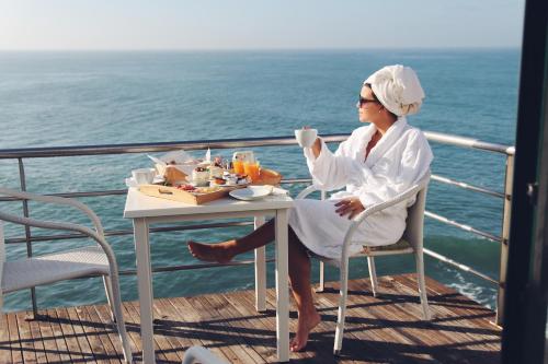 een vrouw aan een tafel met een kopje koffie op een cruiseschip bij Casa d'Arriba in Atouguia da Baleia