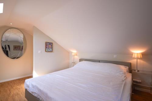 um quarto com uma cama branca e um espelho em Aparthotel Hine Adon Fribourg em Fribourg