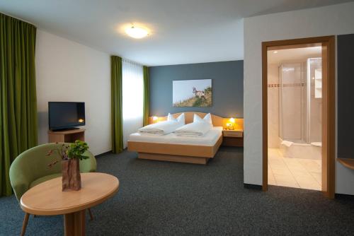 ein Hotelzimmer mit einem Bett und einem TV in der Unterkunft Alpenlodge Pfronten in Pfronten