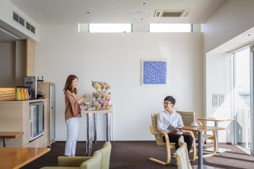 Eine Frau steht in einem Wohnzimmer neben einem Mann. in der Unterkunft Hotel Setre Kobe Maiko in Kōbe