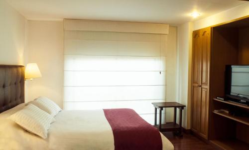 una camera d'albergo con letto e TV di Apartaestudios Los Andes a Bogotá