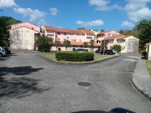 a parking lot with a building and cars parked at Madiana plage in Schœlcher