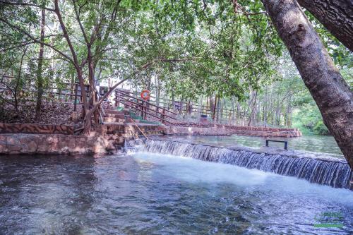 una cascada en medio de un río con árboles en Prime Hotel Águas da Serra, en Rio Quente