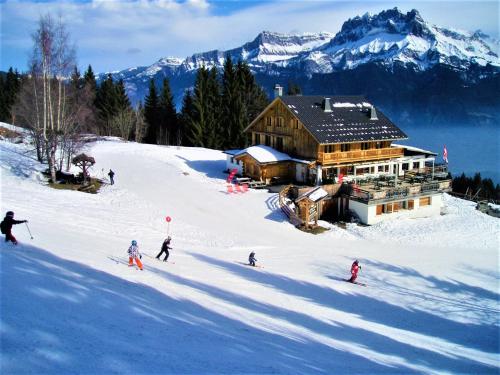 eine Gruppe von Personen, die im Schnee vor einer Lodge Ski fahren in der Unterkunft Le Refuge in Cordon