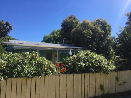 ein Haus hinter einem Zaun mit Büschen und Blumen in der Unterkunft Apollo Bay Backpackers in Apollo Bay