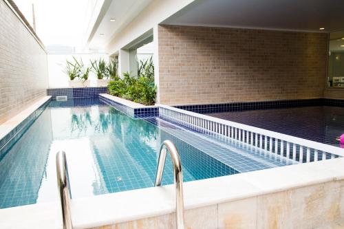 uma piscina com duas cadeiras num edifício em Pousada Villa Di Enzo em Ubatuba