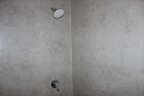 a shower with a stone wall with a shower head at Adi Bali Homestay in Uluwatu