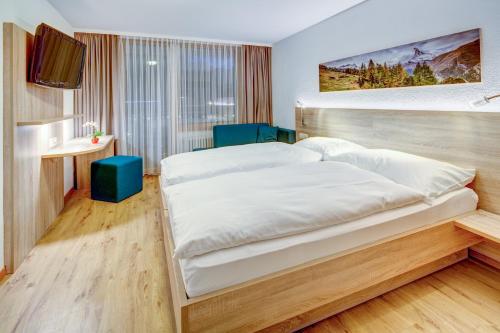 una camera da letto con un grande letto bianco e una televisione di Hotel Matterhorn Inn a Täsch