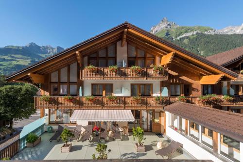 Alpenresort Eienwäldli Engelberg في إنغيلبرغ: مبنى شقق مع شرفة مع طاولات وكراسي