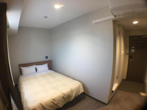 a small bedroom with a bed in a room at Hotel Crown Hills Onahama in Iwaki