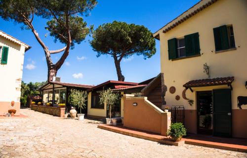 una casa con persianas verdes y árboles en el fondo en Locanda Di Ansedonia - Ristorante GRIGL"io", en Orbetello